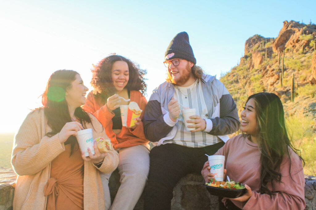 group of young adults hanging out outside with mountain landscape
