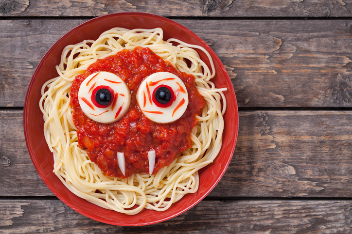 Scary halloween food pasta vampire monster face with big eyes and fangs for celebration party decoration. Vintage wooden background Rustic style