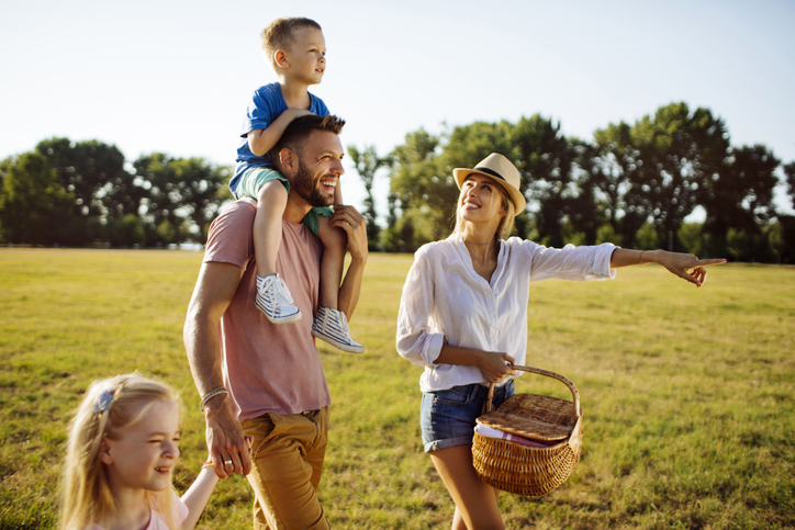 Happy family walking on a beautiful grass field going on a picnic